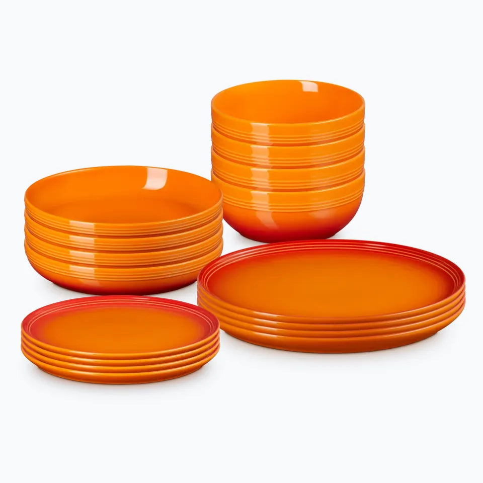 The sixteen piece coupe dinnerware set stacked, in volcanic orange