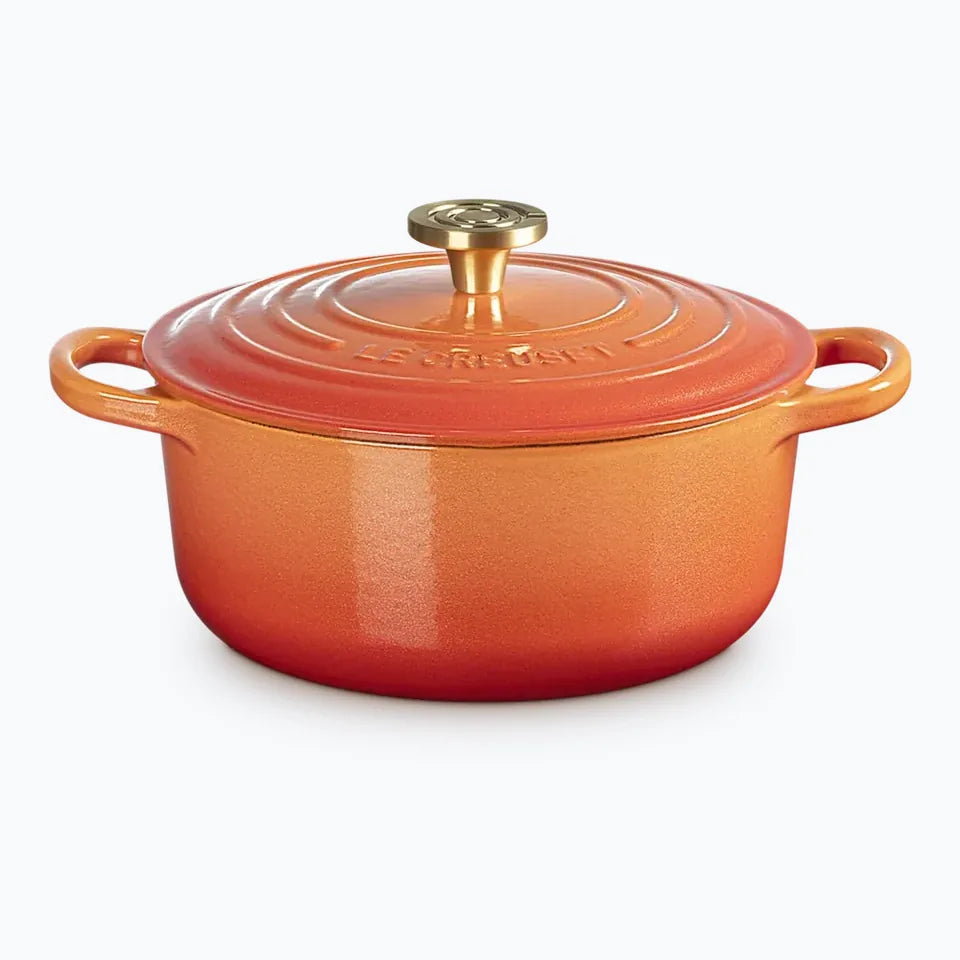 Flamme Dor&eacute;e round casserole with the lid on, graded from orange at the base to gold at the rim, with a brass knob