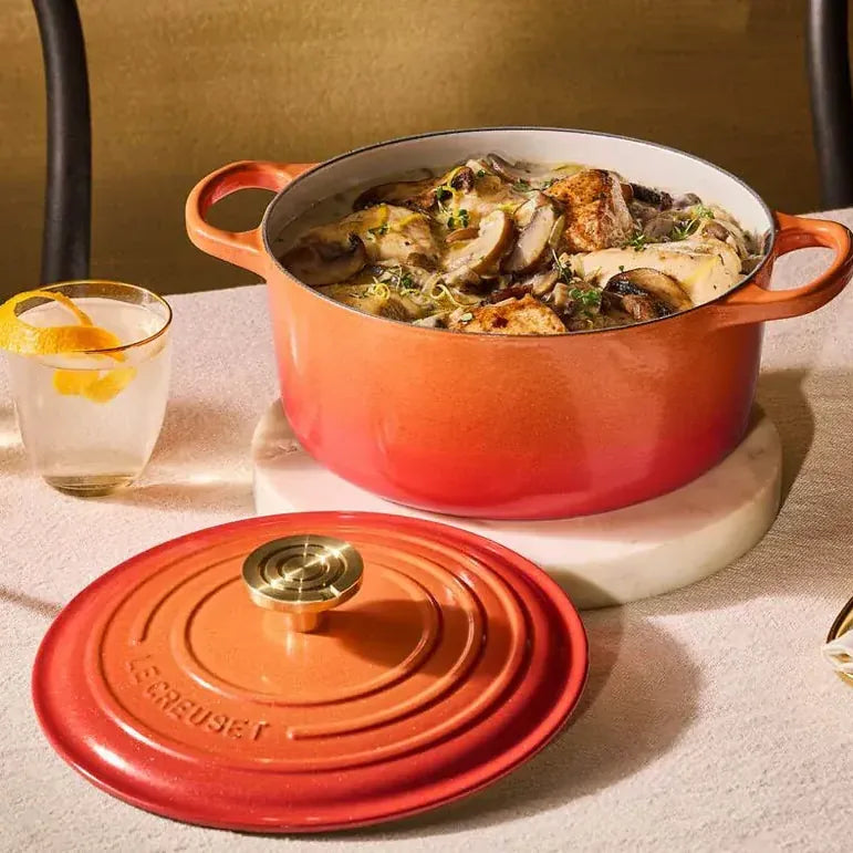 The casserole open and full on a laid table, the lid resting beside it, brass candlesticks and cutlery around