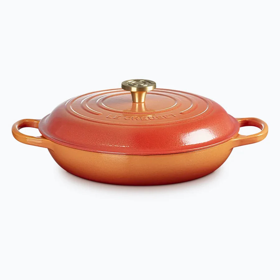 Flamme Doree shallow casserole with the lid on, graded orange to gold with a brass knob